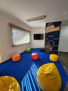 Espaço Criativo da Escola Place com pufes e TV